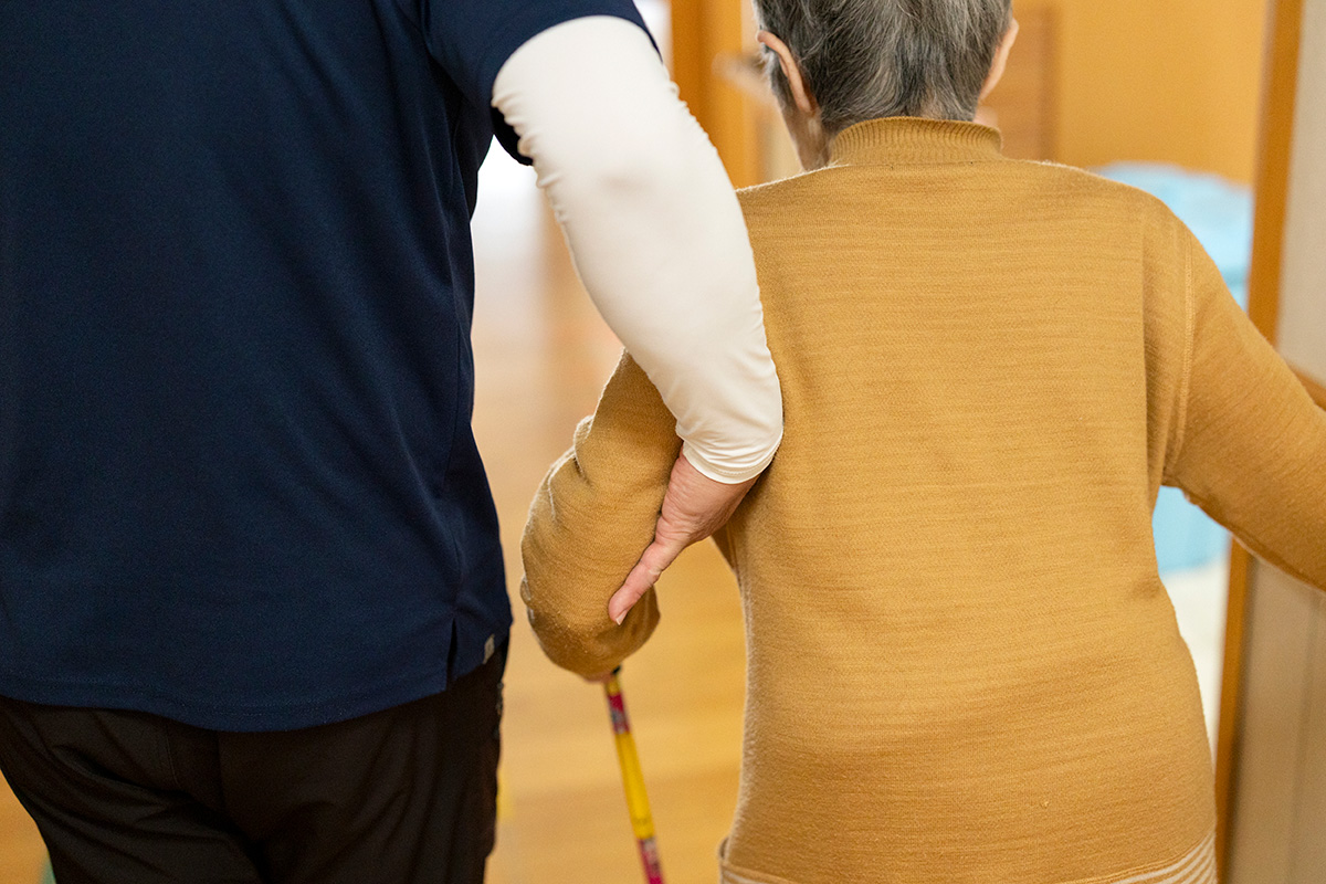 入居者様の手を握り、笑顔で話しかけるスタッフの様子